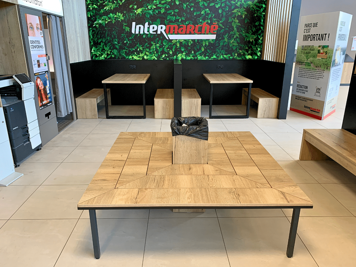 Espace d’attente Intermarché aménagé avec tables, assises et mobilier en bois sur mesure par MSG Vidal Agencement