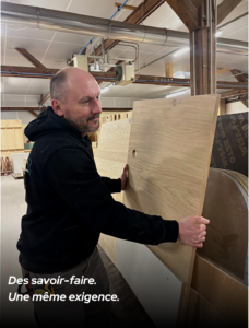 Artisan agenceur manipulant un panneau en bois dans l’atelier de fabrication MSG Vidal Agencement