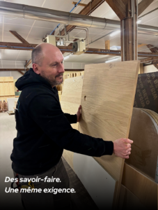 Artisan agenceur manipulant un panneau en bois dans l’atelier de fabrication MSG Vidal Agencement